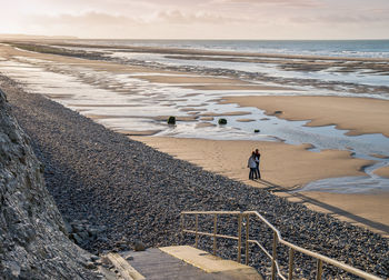 High angle view of people standing at beach against sky