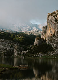 Scenic view of lake by rocks against sky