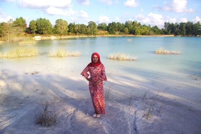 Woman standing by lake against sky