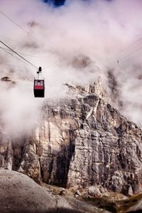Overhead cable car over mountains against sky foggy weather