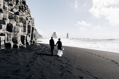 People on beach by sea against sky