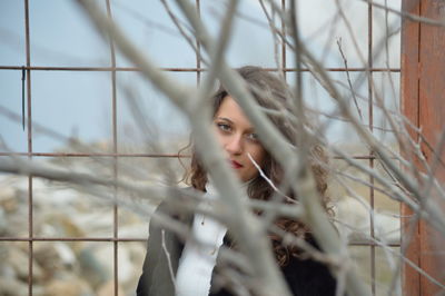 Portrait of young woman against fence