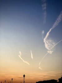 Low angle view of vapor trails in sky during sunset