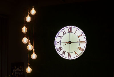 Low angle view of illuminated light bulb hanging on ceiling