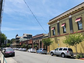 Cars on road by buildings in city against sky