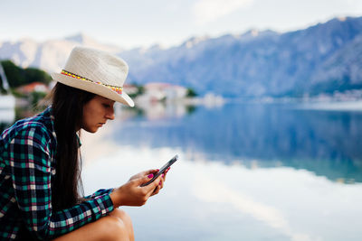 Close-up of man using mobile phone against sky