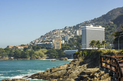 Buildings by sea against clear sky