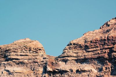 Low angle view of rock formations against clear blue sky