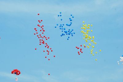 Low angle view of colorful balloons flying against clear sky