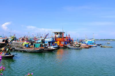 Fishing boats moored at harbor against sky