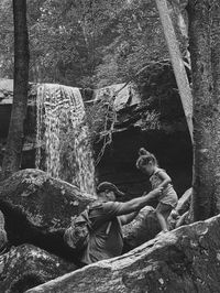 Low angle view of child standing on rock with dad holding her hands