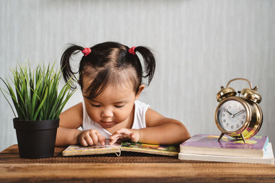 Girl reading book on table at home