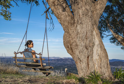 Woman sitting on swing seat overlooking the bush in new south wales