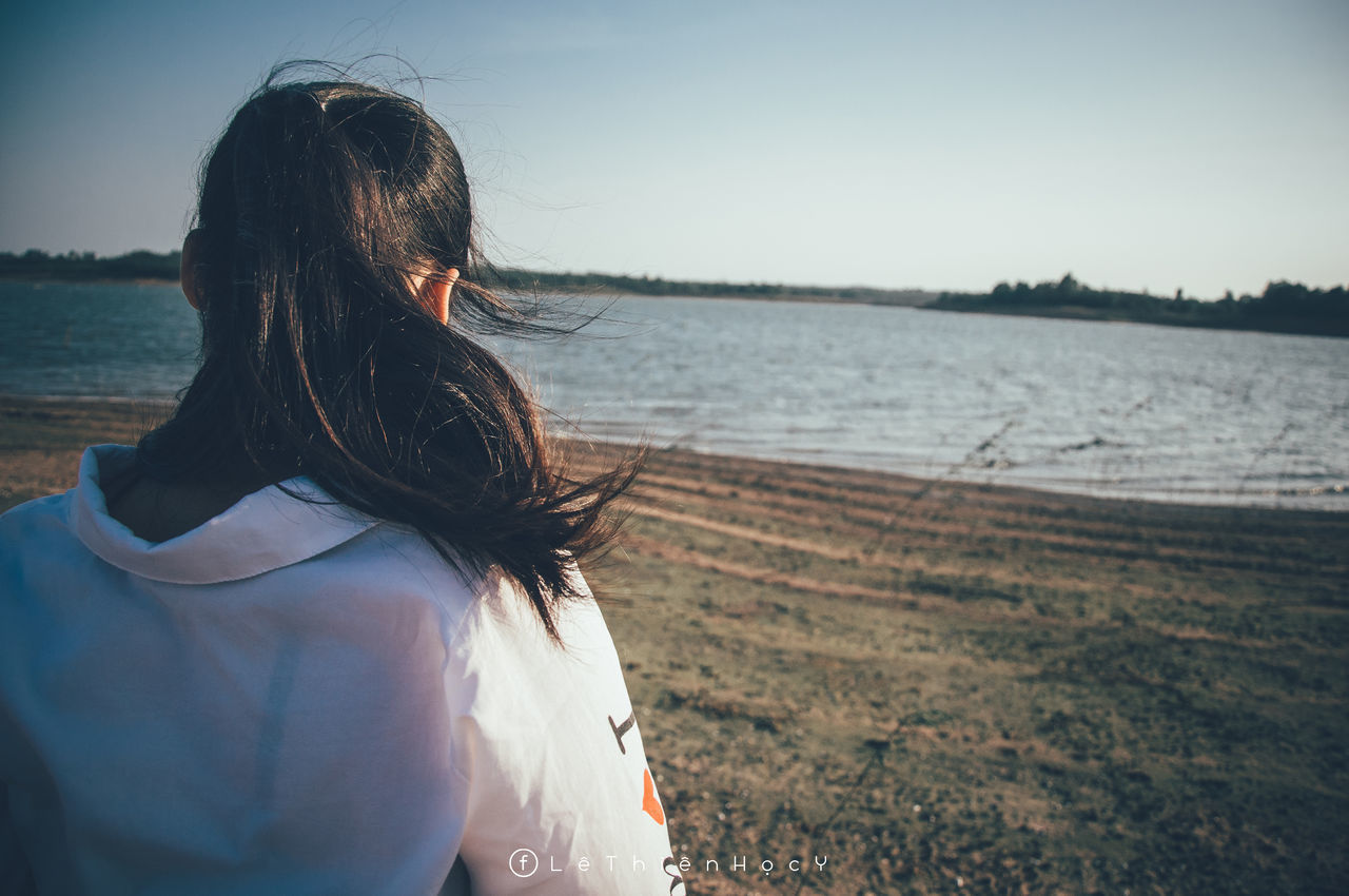 REAR VIEW OF WOMAN LOOKING AT BEACH AGAINST SKY