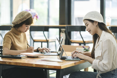Young woman using mobile phone while sitting on table