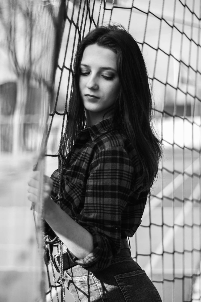 one person, young adult, long hair, real people, hair, young women, hairstyle, lifestyles, casual clothing, fence, barrier, beauty, leisure activity, portrait, beautiful woman, standing, boundary, looking, outdoors, contemplation, teenager