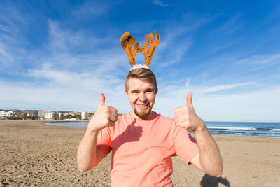 Portrait of smiling man standing at beach against sky