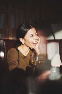 Laughing woman looking away while sitting at restaurant