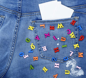 High angle view of blank papers with colorful alphabets on jeans