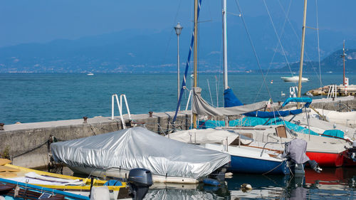Boats moored in sea against blue sky