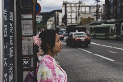 Woman looking away on road in city