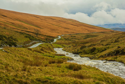 Scenic view of stream amidst landscape against sky