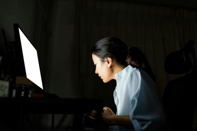 Side view of a woman working on computer 