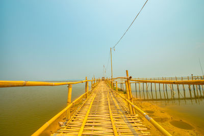 Bridge over calm sea against clear sky