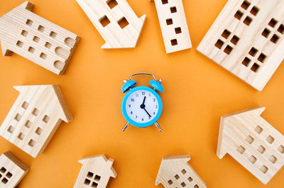 A blue alarm clock and many wooden houses around. mortgage and loan concept. 