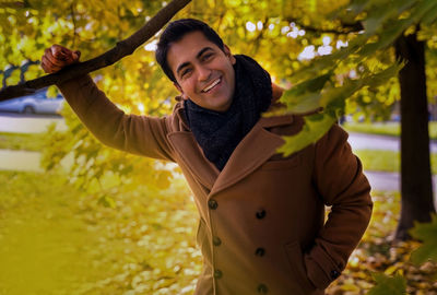 Portrait of young woman standing against trees