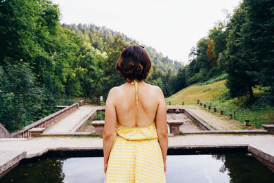 Rear view of woman standing against river