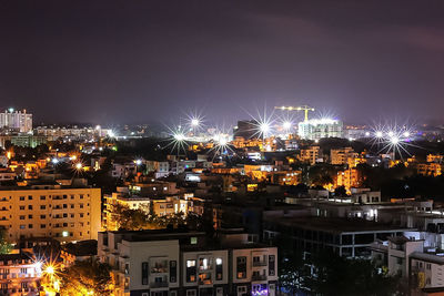 Illuminated cityscape against sky at night