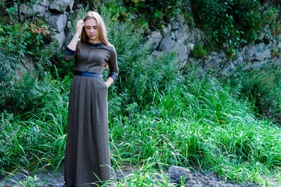 Young woman in dress standing against rock formation