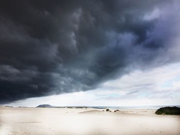 Scenic view of beach against cloudy sky during stormy weather