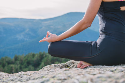 Midsection of woman sitting on rock at beach