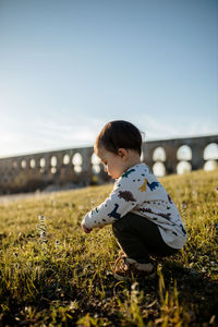 Full length of child crouching on grass outdoors