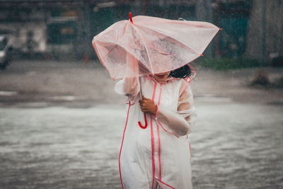 Woman with umbrella walking against sea