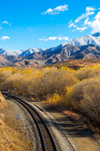 Railroad tracks by snowcapped mountains against sky