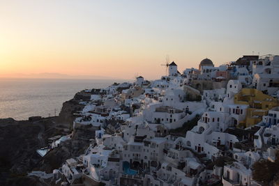 Aerial view of townscape by sea against sky during sunset