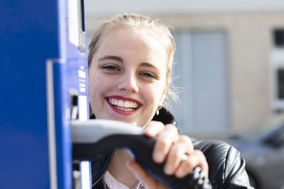 Portrait of a smiling young woman holding camera