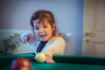 Cute girl playing pool at home