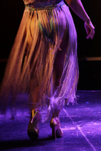 Low section of woman standing on illuminated stage