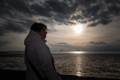 Man looking at sea against sky during sunset