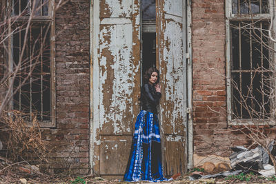 Portrait of woman standing against abandoned building