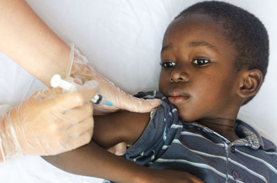 Cropped hands of doctor injecting boy in hospital
