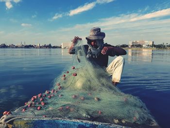 Fisherman with fishing net in boat on lake