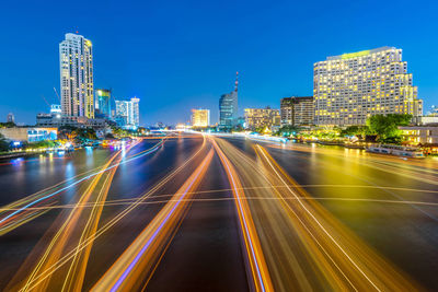 Light trails on road amidst buildings in city at night