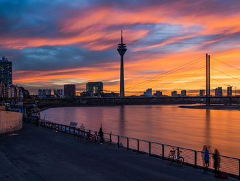 Low angle view of silhouette bridge over river against cloudy sky during sunset