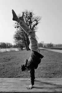 Boy doing handstand on wooden bench