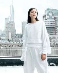 Young woman standing against white buildings in city